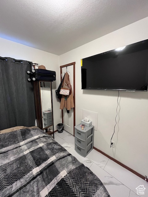 Bedroom featuring baseboards, a textured ceiling, and marble finish floor