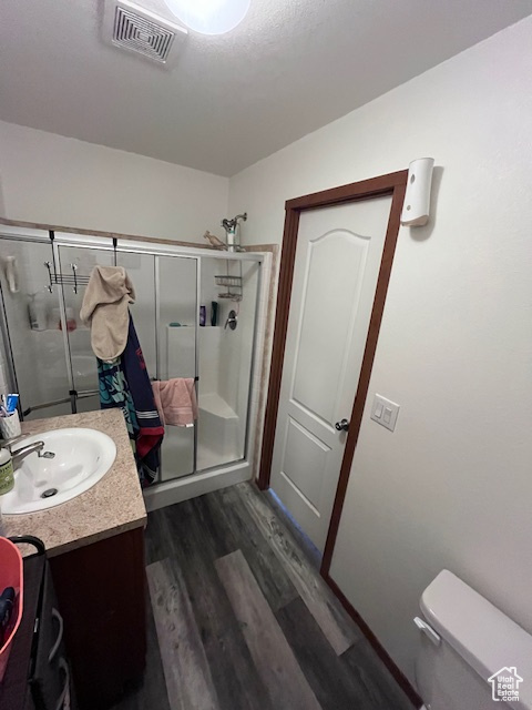 Bathroom with vanity, toilet, a shower stall, wood finished floors, and visible vents
