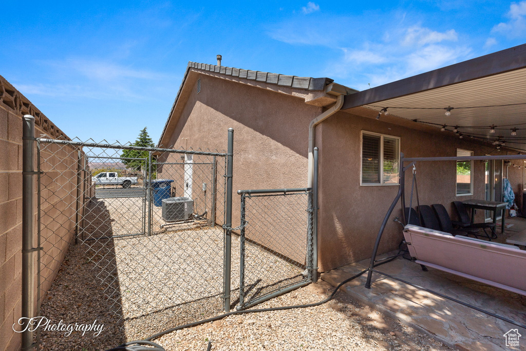 View of side of property featuring fence, a gate, and stucco siding