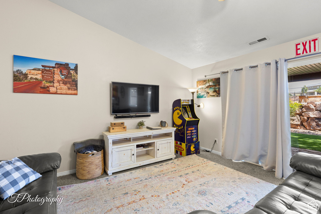 Living area with carpet floors, baseboards, lofted ceiling, and visible vents