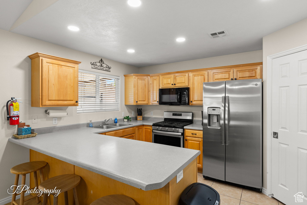 Kitchen with a peninsula, a kitchen bar, recessed lighting, a sink, and stainless steel appliances