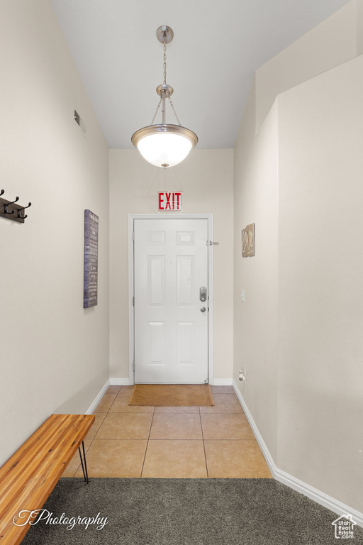 Entryway featuring visible vents, baseboards, light tile patterned floors, and light colored carpet