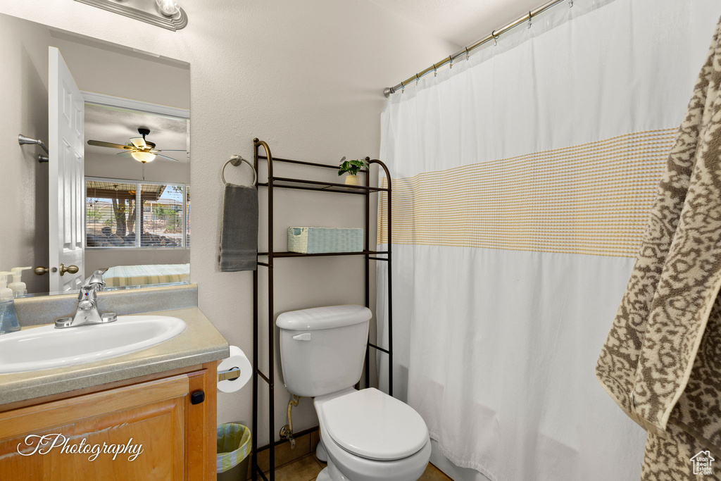 Bathroom featuring toilet, ceiling fan, a shower with curtain, and vanity