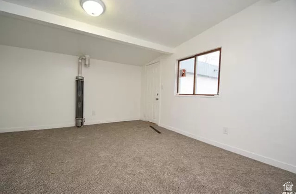Carpeted spare room with baseboards and lofted ceiling with beams