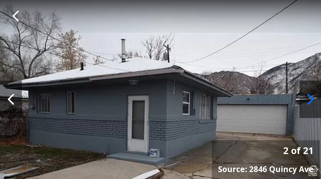 View of front of home featuring an outdoor structure, a mountain view, and a garage