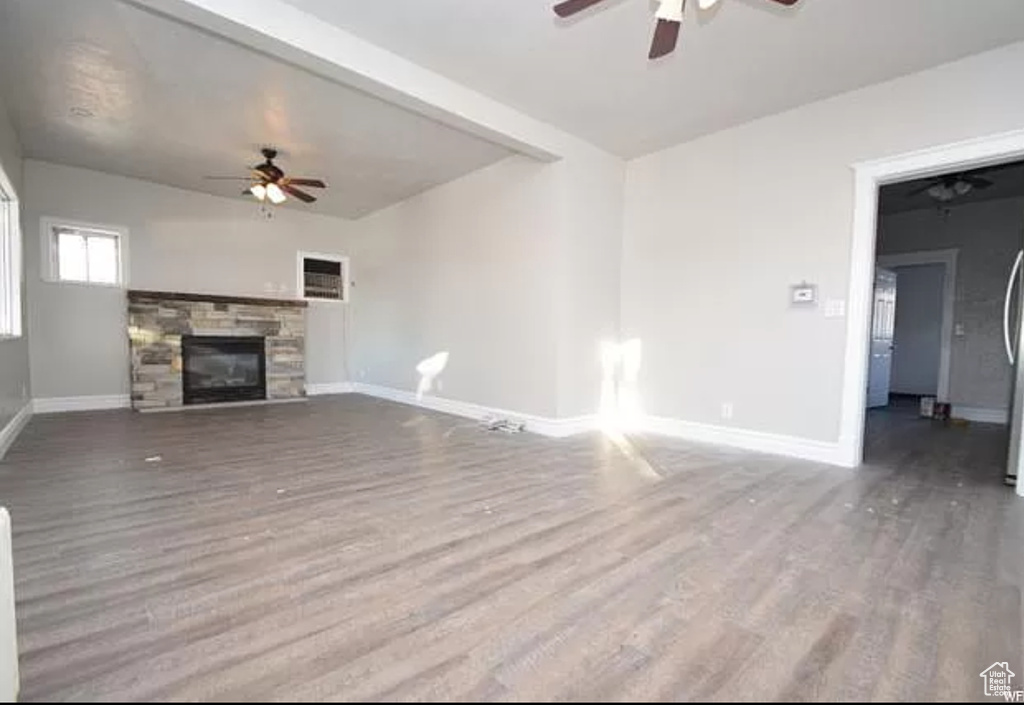 Unfurnished living room with baseboards, a ceiling fan, wood finished floors, and a fireplace