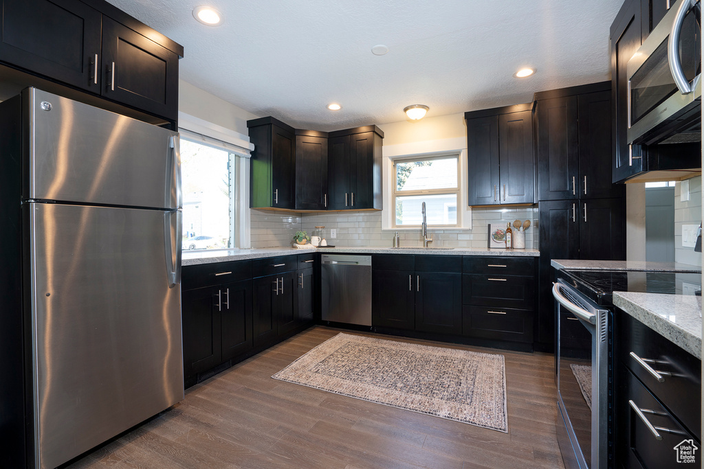 Kitchen with a sink, decorative backsplash, stainless steel appliances, and a wealth of natural light