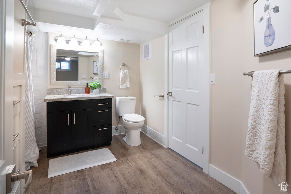 Bathroom featuring vanity, toilet, baseboards, wood finished floors, and visible vents