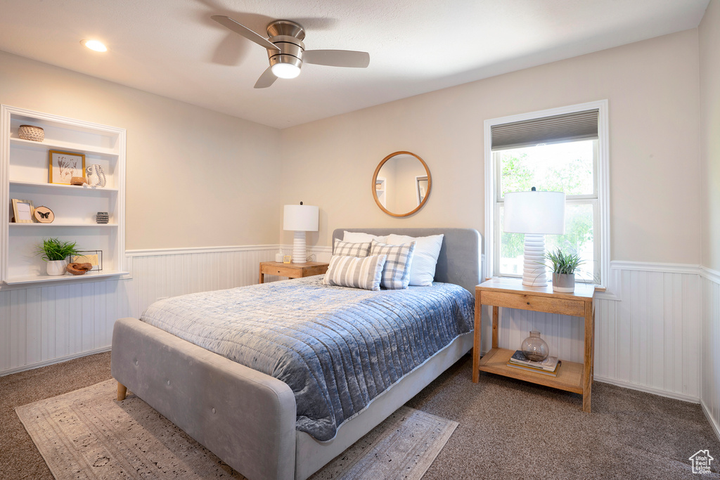 Bedroom with carpet floors, ceiling fan, and a wainscoted wall