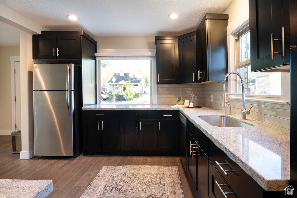 Kitchen with a sink, appliances with stainless steel finishes, tasteful backsplash, and light wood-type flooring