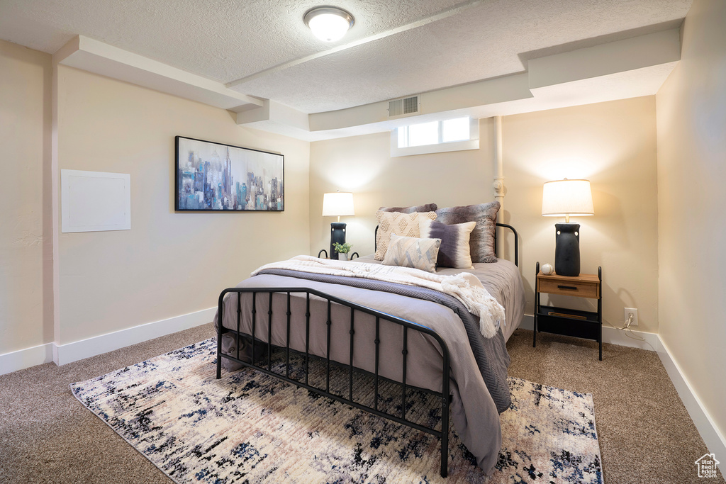 Carpeted bedroom with baseboards, a textured ceiling, and visible vents