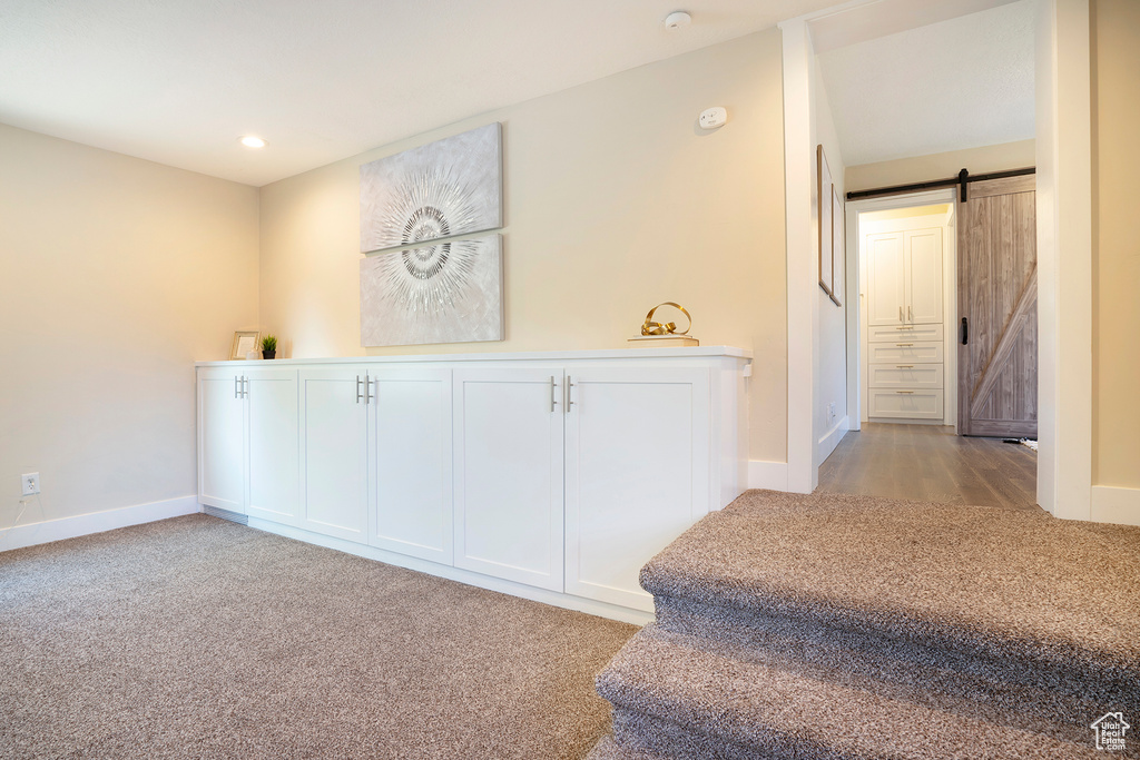 Corridor featuring recessed lighting, baseboards, light colored carpet, and a barn door