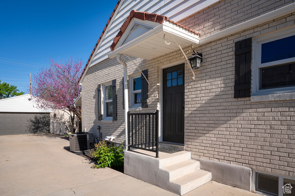 Doorway to property with central AC and brick siding