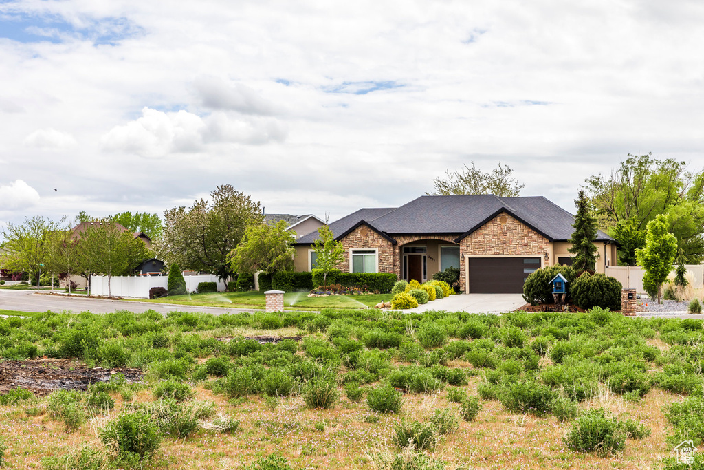 Ranch-style house with concrete driveway, stone siding, and a garage