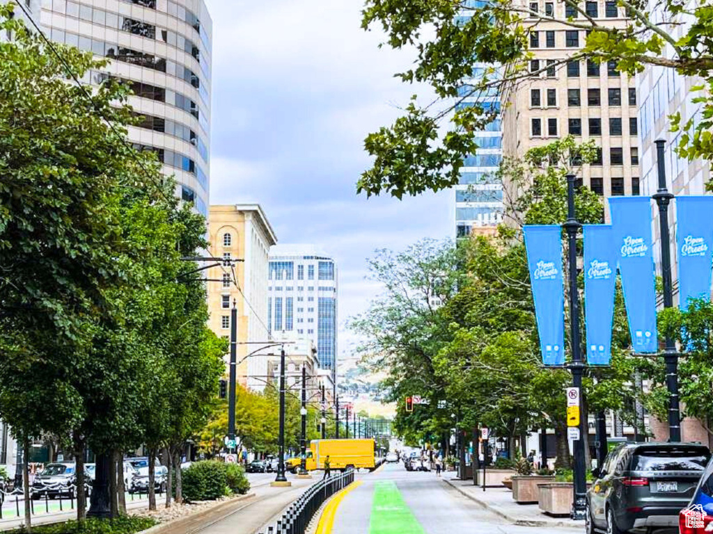 View of road featuring traffic lights, curbs, street lights, and sidewalks