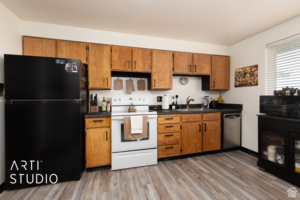 Kitchen featuring brown cabinetry, a sink, black appliances, and light wood finished floors