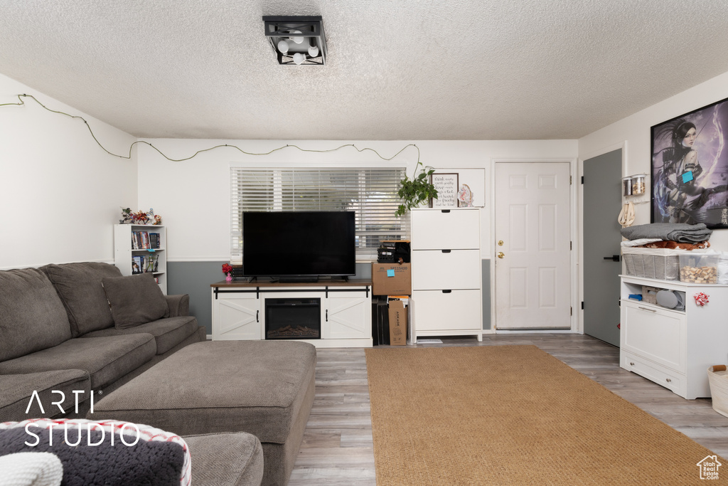 Living area with a textured ceiling and light wood-style flooring
