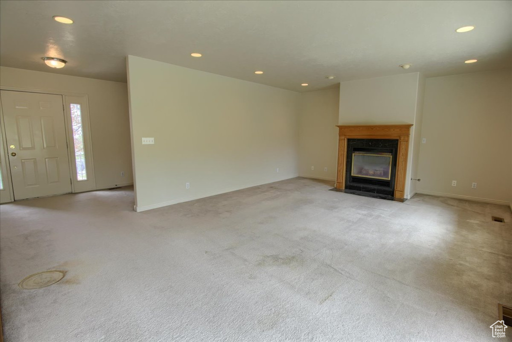 Unfurnished living room with recessed lighting, a fireplace with flush hearth, baseboards, and light carpet