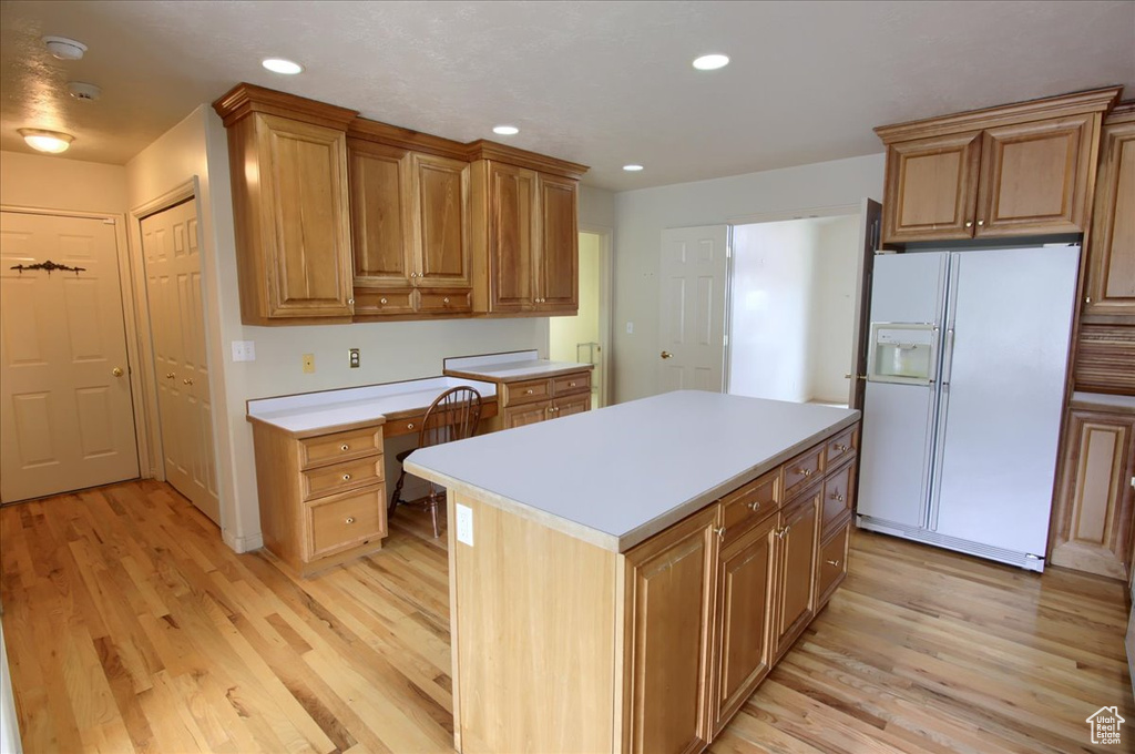 Kitchen featuring a center island, white refrigerator with ice dispenser, light countertops, light wood finished floors, and recessed lighting