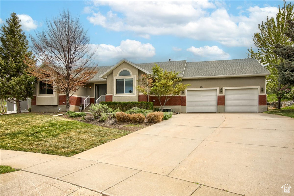 Ranch-style house with stucco siding, driveway, a front yard, and a garage