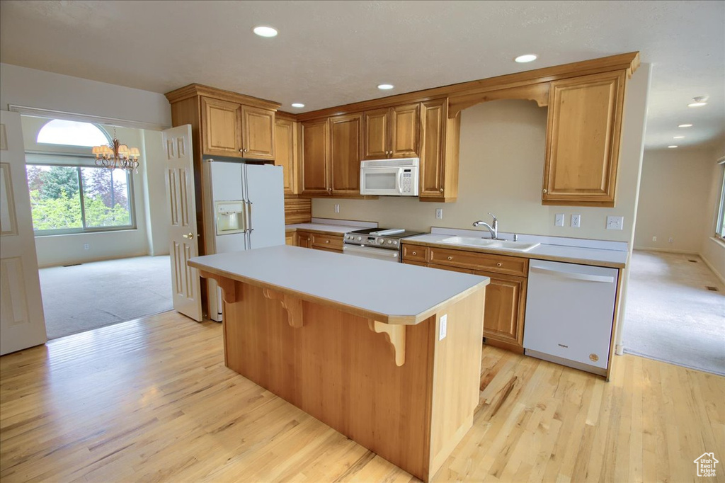 Kitchen with a sink, light countertops, light wood-style floors, recessed lighting, and white appliances