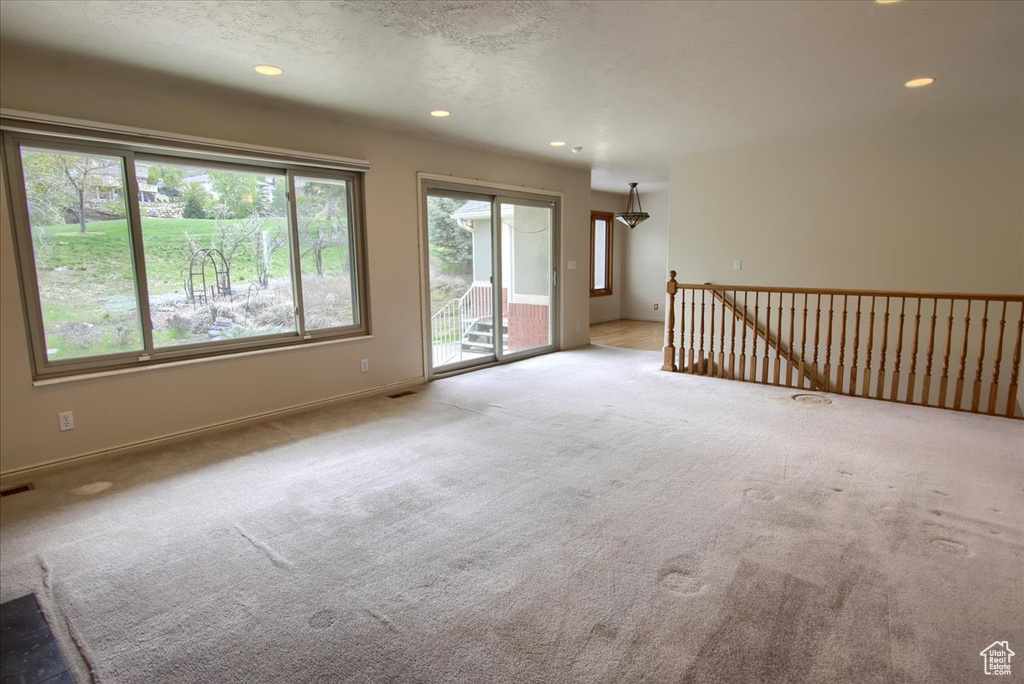Unfurnished living room with baseboards, carpet flooring, visible vents, and recessed lighting