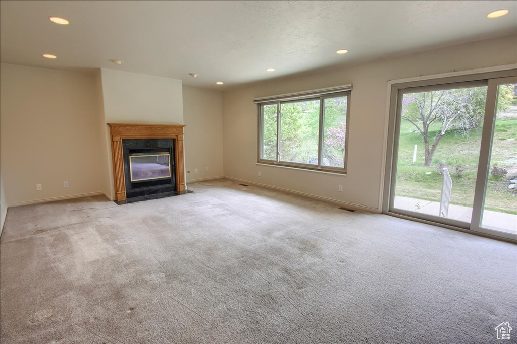 Unfurnished living room with carpet flooring, recessed lighting, baseboards, and a high end fireplace