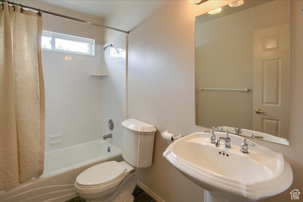 Full bathroom with a sink, baseboards, toilet, and shower / tub combo