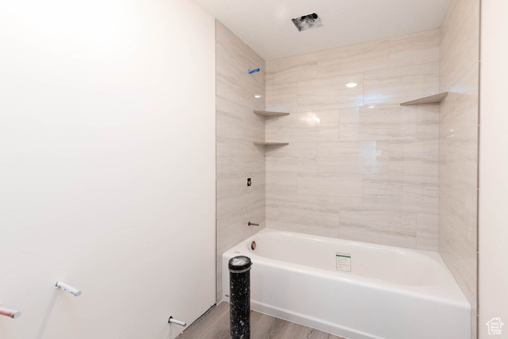 Full bath featuring shower / washtub combination and wood finished floors