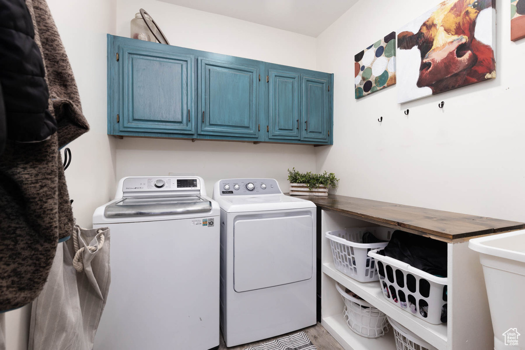 Laundry room featuring washer and clothes dryer, cabinet space, and wood finished floors