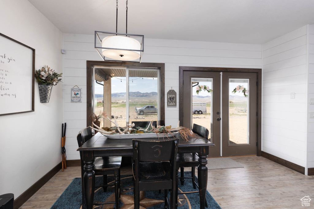 Dining room featuring french doors, wooden walls, baseboards, and wood finished floors
