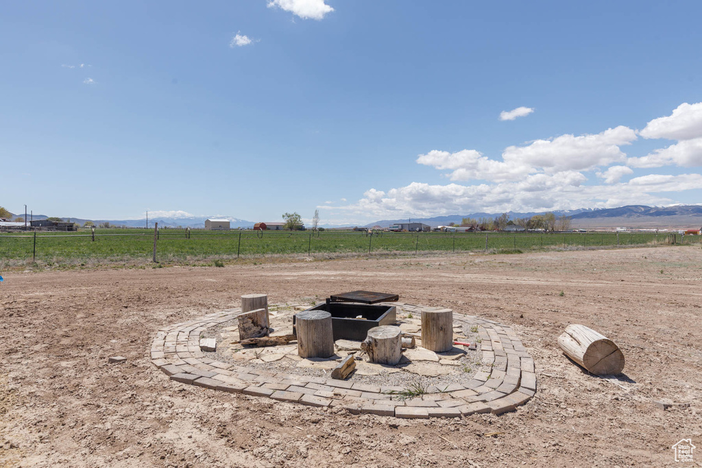 View of yard featuring a rural view, fence, a mountain view, and an outdoor fire pit