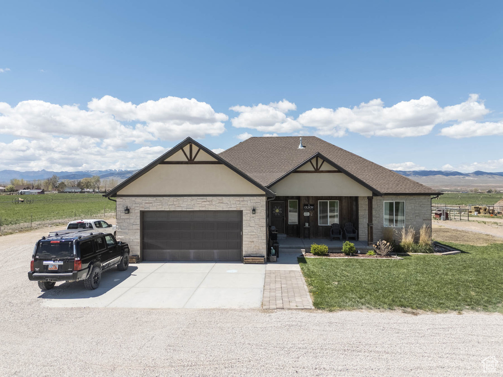 Craftsman-style house featuring a front lawn, covered porch, concrete driveway, an attached garage, and a mountain view