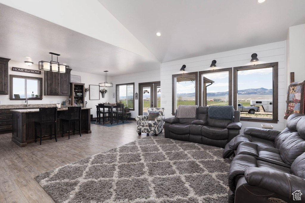 Living area featuring light wood-style floors, vaulted ceiling, and a wealth of natural light