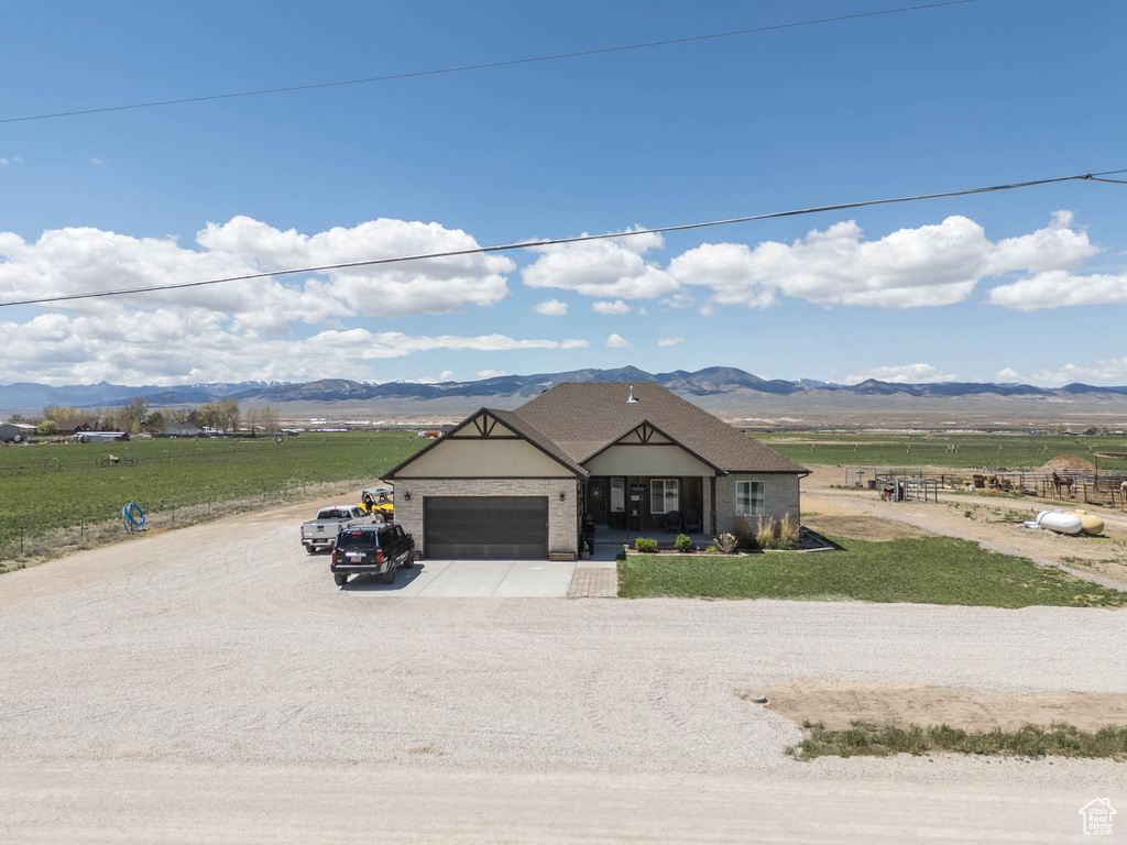 View of front of home featuring a mountain view, an attached garage, driveway, and a rural view