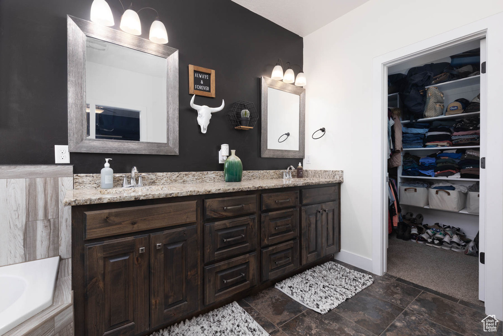 Full bathroom featuring double vanity, a sink, baseboards, and a walk in closet