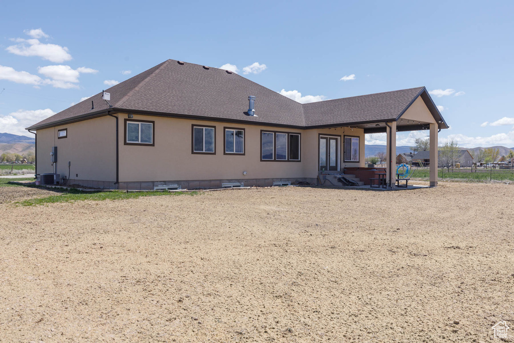 Back of house with central air condition unit, a patio, and a shingled roof