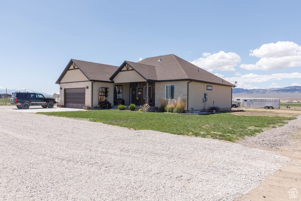 View of front of property featuring driveway, roof with shingles, a front yard, a garage, and brick siding