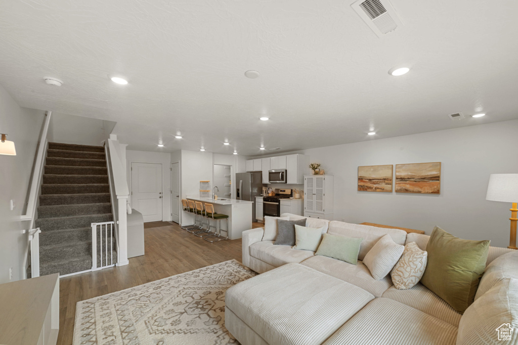 Living room featuring recessed lighting, stairway, light wood finished floors, and visible vents