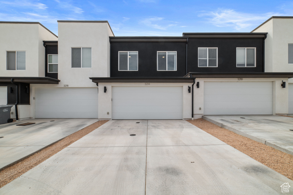 Townhome / multi-family property featuring an attached garage, driveway, and stucco siding