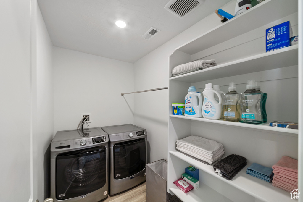 Laundry area featuring visible vents, laundry area, light wood finished floors, and washer and dryer