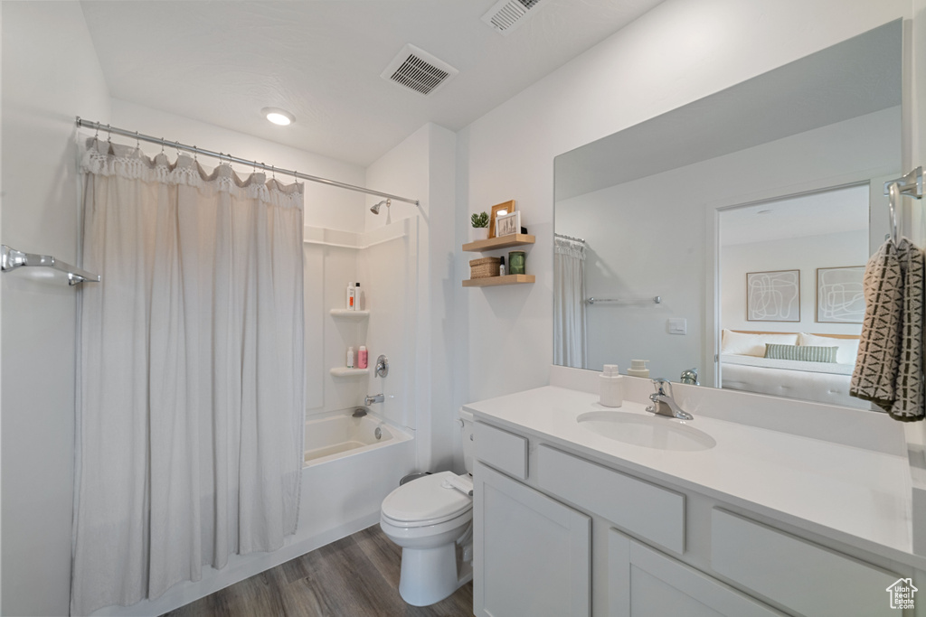 Full bath with vanity, toilet, wood finished floors, and visible vents