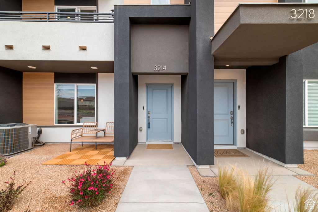 Doorway to property with central AC and stucco siding