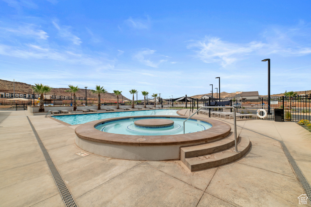 Community pool featuring fence, a community hot tub, and a residential view
