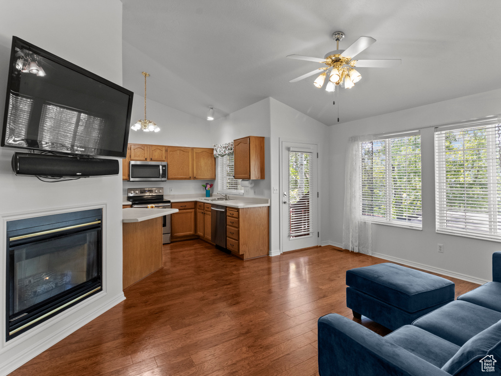 Kitchen with a sink, light countertops, brown cabinetry, stainless steel appliances, and open floor plan