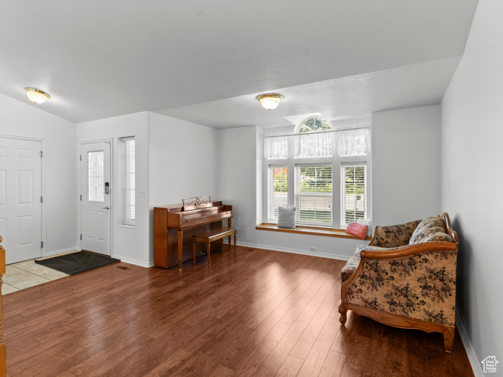 Foyer featuring baseboards, lofted ceiling, and wood finished floors