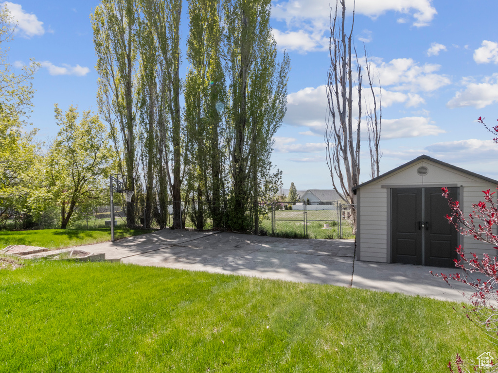 View of yard with an outdoor structure, fence, and a storage shed