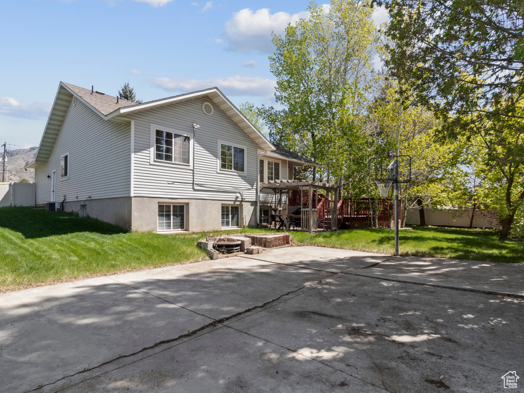 Rear view of property with a lawn, an outdoor fire pit, fence, and a deck