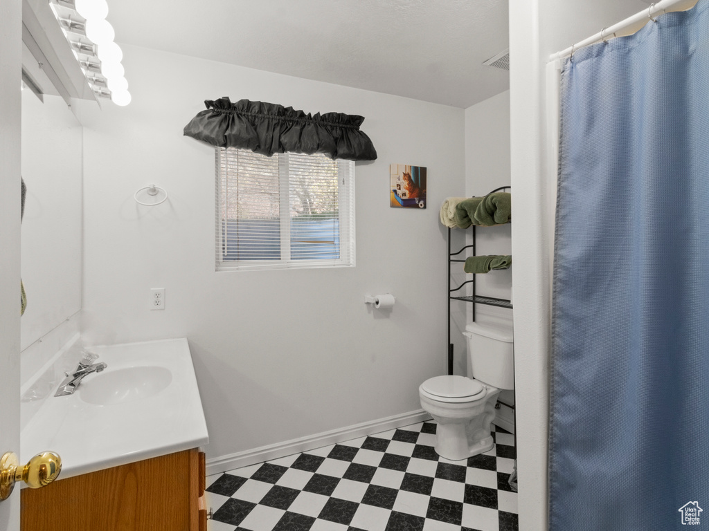 Full bathroom featuring vanity, baseboards, tile patterned floors, and toilet