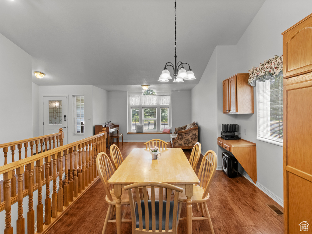 Dining area with visible vents, an inviting chandelier, baseboards, dark wood-style floors, and vaulted ceiling
